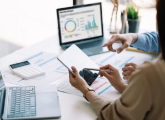 Inteligencia artificial: regular sí, pero con inteligencia Dos personas trabajan con dispositivos digitales y analizan información en una computadora, representando el uso responsable de la inteligencia artificial como herramienta de apoyo profesional.
