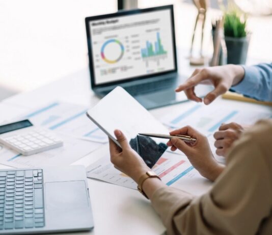 Inteligencia artificial: regular sí, pero con inteligencia Dos personas trabajan con dispositivos digitales y analizan información en una computadora, representando el uso responsable de la inteligencia artificial como herramienta de apoyo profesional.