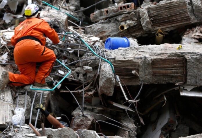 Ayuda a Colombia Rescatista busca sobrevivientes entre los escombros de una construcción colapsada tras un terremoto.