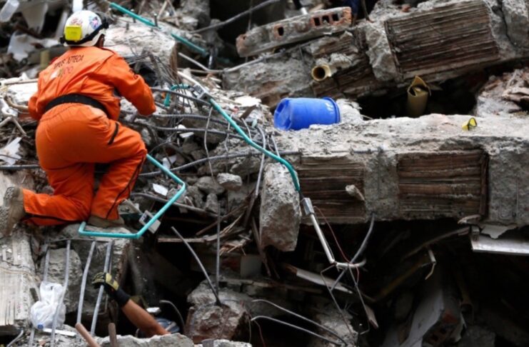 Colombia: la ideología se interpone entre la ayuda y las víctimas Rescatista busca sobrevivientes entre los escombros de una construcción colapsada tras un terremoto.