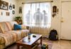 El miedo como política migratoria: lo que ocurre detrás de las redadas de ICE Sala de un hogar latino en Estados Unidos con juguetes, fotografías familiares y una mochila; detrás de las cortinas de una ventana aparecen las siluetas de agentes de ICE.