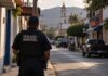 Municipios bajo presión: el crimen organizado supera la capacidad local Policía municipal de espaldas observa una calle de una comunidad mexicana, como representación de la vulnerabilidad de las autoridades locales frente al crimen organizado.