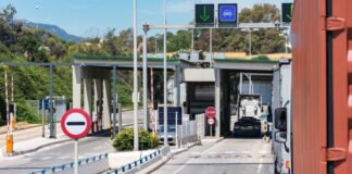 México no pagó el muro: los aranceles se cobran en Estados Unidos Camiones de carga circulan por carriles de un puesto de control con casetas, barreras y señales de tránsito.