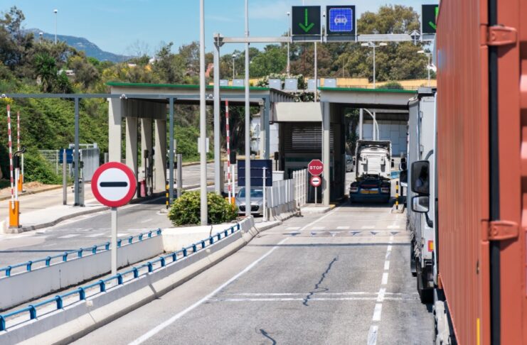 México no pagó el muro: los aranceles se cobran en Estados Unidos Camiones de carga circulan por carriles de un puesto de control con casetas, barreras y señales de tránsito.