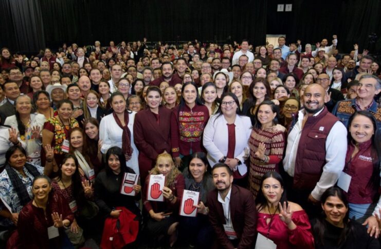 Morena aprueba alianzas para 2027 y pone en marcha su organización territorial Grupo numeroso de integrantes de Morena posa frente a cortinas negras; varias personas levantan las manos y muestran acreditaciones del partido.