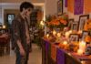 Entre zombis y calaveras: una tradición necesita más que adornos Joven disfrazado de zombi contempla una ofrenda doméstica con fotografías familiares, cempasúchil, veladoras y pan de muerto.