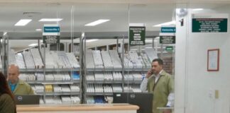 El faltante de medicamentos y las cifras manipuladas para desacreditar al sistema de salud en México Personal detrás de las ventanillas de una farmacia hospitalaria, con medicamentos organizados en anaqueles y una usuaria frente al mostrador.