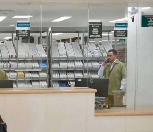 El faltante de medicamentos y las cifras manipuladas para desacreditar al sistema de salud en México Personal detrás de las ventanillas de una farmacia hospitalaria, con medicamentos organizados en anaqueles y una usuaria frente al mostrador.