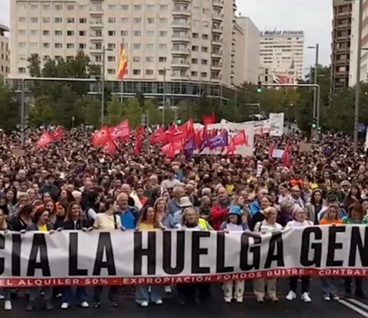 Sindicatos españoles anuncian huelga general por la crisis de vivienda Multitud en una manifestación por la vivienda, con banderas y una pancarta que llama a la huelga general.