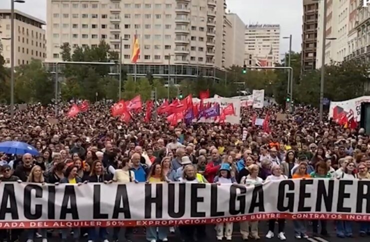 Sindicatos españoles anuncian huelga general por la crisis de vivienda Multitud en una manifestación por la vivienda, con banderas y una pancarta que llama a la huelga general.