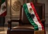 Una investidura manchada Banda presidencial mexicana con una mancha de tinta negra, colocada sobre el respaldo de una silla vacía.