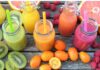 Jugos de fruta: aunque sea natural también necesita medida Vaso de jugo de naranja junto a un plato con naranja, toronja, kiwi y frambuesas sobre una mesa de madera.