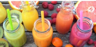 Jugos de fruta: aunque sea natural también necesita medida Vaso de jugo de naranja junto a un plato con naranja, toronja, kiwi y frambuesas sobre una mesa de madera.