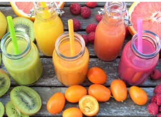 Jugos de fruta: aunque sea natural también necesita medida Vaso de jugo de naranja junto a un plato con naranja, toronja, kiwi y frambuesas sobre una mesa de madera.