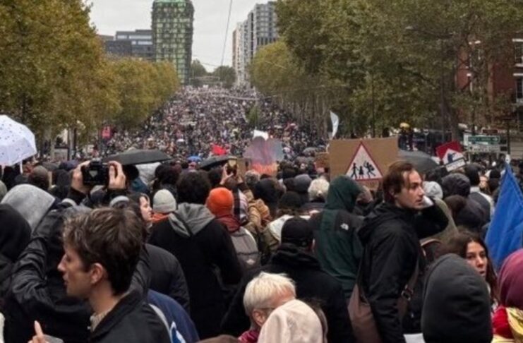 Francia vuelve a las calles pese a los toques de queda y el despliegue policial Multitud de manifestantes con pancartas y paraguas en una amplia avenida arbolada.