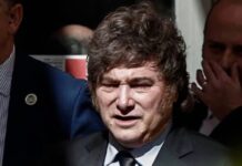 Milei en España: llama dictador, corrupto y ladrón al presidente español Javier Milei, con traje oscuro y corbata, rodeado de otras personas.