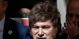 Milei en España: llama dictador, corrupto y ladrón al presidente español Javier Milei, con traje oscuro y corbata, rodeado de otras personas.