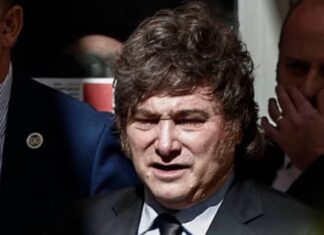 Milei en España: llama dictador, corrupto y ladrón al presidente español Javier Milei, con traje oscuro y corbata, rodeado de otras personas.