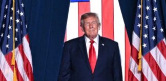 Donald Trump descalifica a Noruega por no otorgarle el premio Nobel de la Paz Donald Trump, con traje oscuro y corbata roja, frente a varias banderas de Estados Unidos.