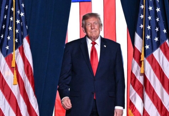 Trump pretendía en Nobel Donald Trump, con traje oscuro y corbata roja, frente a varias banderas de Estados Unidos.