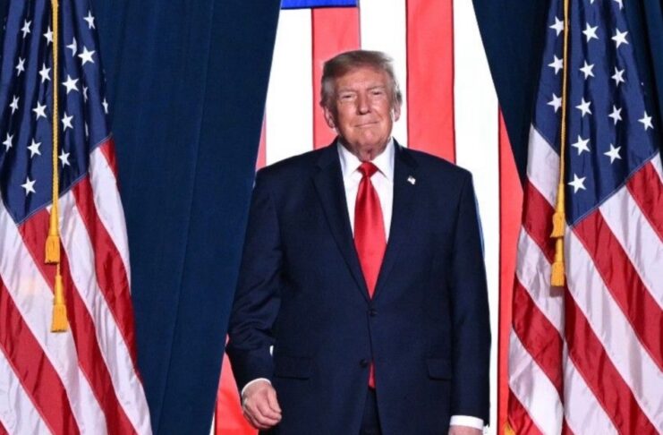 Donald Trump descalifica a Noruega por no otorgarle el premio Nobel de la Paz Donald Trump, con traje oscuro y corbata roja, frente a varias banderas de Estados Unidos.